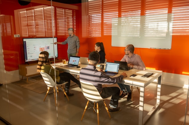 The picture shows a person presenting data to a small group of people at a conference table.